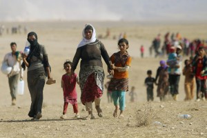 Displaced people from the minority Yazidi sect, fleeing violence from forces loyal to the Islamic State in Sinjar town, walk towards the Syrian border, on the outskirts of Sinjar mountain, near the Syrian border town of Elierbeh of Al-Hasakah Governorate